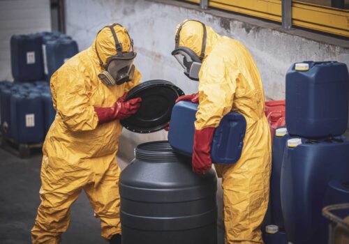 Chemical plant workers in hazmat suit mixing chemicals and manufacturing acids for heavy industry.